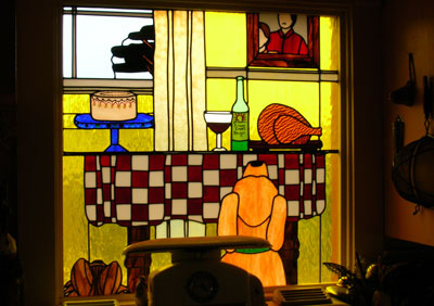 Stained Glass of dog looking at a table full of food.